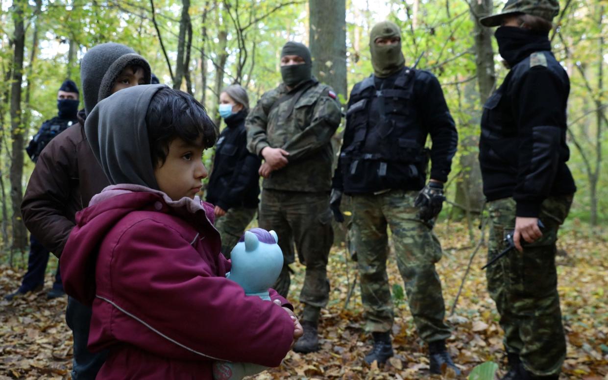 An Iraqi migrant child faces border guards and police officers after they crossed the Belarusian-Polish border - /Reuters/Kacper Pempel 