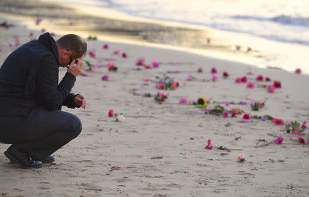 A man reacts near scattered flowers during a vigil for Justine Damond, who was shot by a Minneapolis police officer over the weekend, at Sydney's Freshwater Beach in Australia, July 19, 2017. AAP/Dean Lewins/via REUTERS