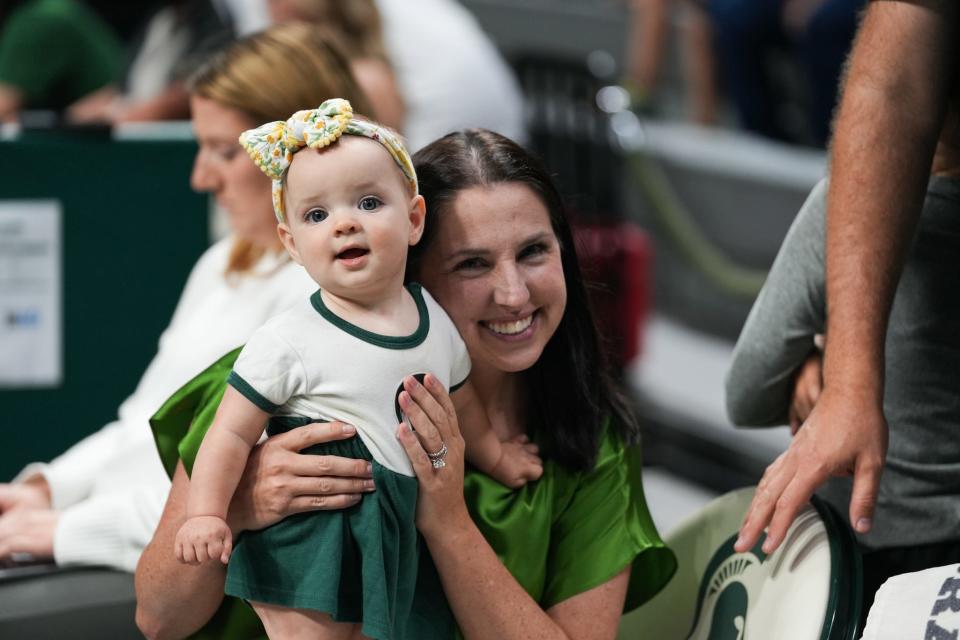 MSU volleyball coach Leah Johnson holds her youngest daughter, Roz, at a match at Breslin Center last season.
