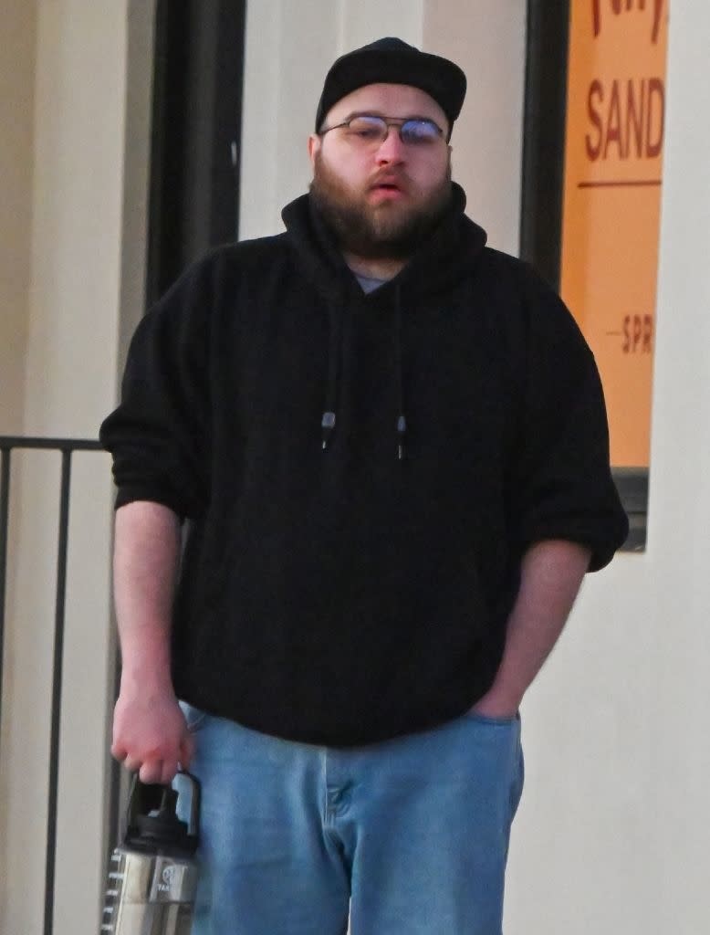 closeup of him walking outside in a hoodie and hat