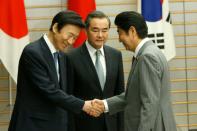 Japanese Prime Minister Shinzo Abe (R) greets South Korean Foreign Minister Yun Byung-Se (L) and Chinese Foreign Minister Wang Yi during their meeting in Tokyo, on August 24, 2016 The ministers held their first talks in more than a year just hours after North Korea fired a ballistic missile from a submarine towards Japan