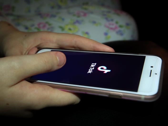 A young girl uses the TikTok app on a smartphone.