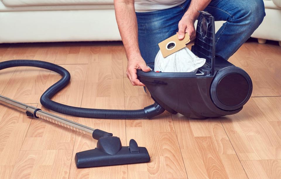 man removing vacuum cleaner bag from vacuum