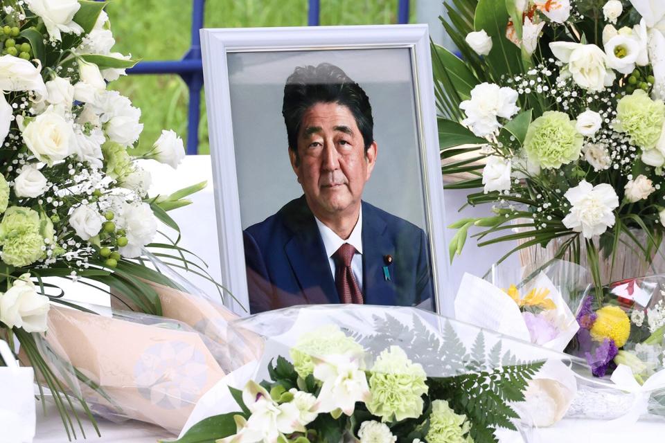 A portrait of late Prime Minister Shinzo Abe is displayed as people sing the books of condolences for Abe at the ruling Liberal Democraatic Party (LDP) headquarters in Tokyo