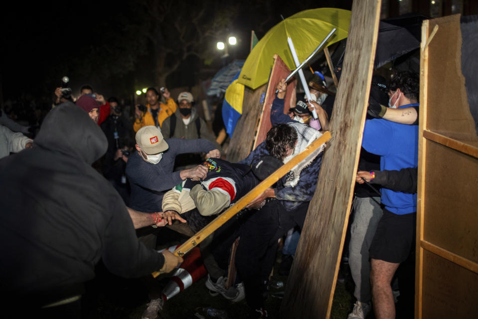 Manifestantes se enfrentan en un campamento propalestino en la UCLA la madrugada del miércoles 1 de mayo de 2024, en Los Ángeles. (AP Foto/Ethan Swope)