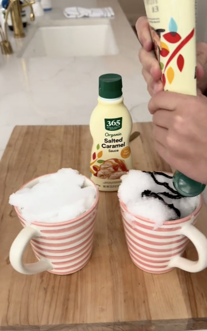 a screenshot from reese witherspoon's tiktok of someone pouring chocolate syrup onto a mug of snow