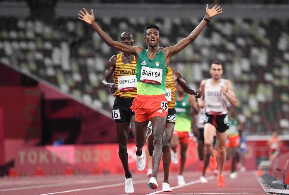 <p>Ethiopia's Selemon Barega (C) celebrate as he crosses the finish line to win ahead of second-placed Uganda's Joshua Cheptegei (L) in the men's 10000m final during the Tokyo 2020 Olympic Games at the Olympic Stadium in Tokyo on July 30, 2021. (Photo by Jewel SAMAD / AFP) (Photo by JEWEL SAMAD/AFP via Getty Images)</p> 