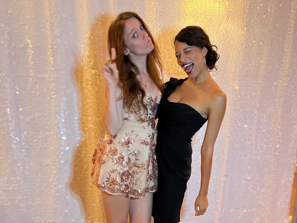 Joanna and a friend posing in front of a glitter backdrop at a wedding.