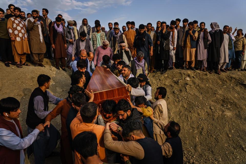 Caskets are carried toward the gravesite as relatives and friends attend a mass funeral.