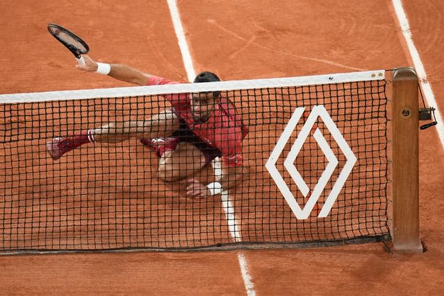 Novak Djokovic falls chasing down a ball at the net against Pierre-Hugues Herbert