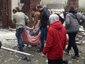 In this photo provided by the Kyiv Regional Police, people carry a body at the scene of a Russian shelling in Kyiv, Ukraine, Wednesday, Nov. 23, 2022. Authorities reported power outages in multiple cities of Ukraine, including parts of Kyiv, and in neighboring Moldova after renewed strikes on Wednesday struck Ukrainian infrastructure facilities. (Kyiv Regional Police via AP)