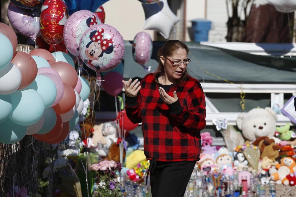 A woman pauses in front of a makeshift memorial Thursday, Jan. 23, 2020, in front of the home where Rachel Henry was arrested on suspicion of killing her three children after they were found dead inside the family home earlier in the week, in Phoenix. (AP Photo/Ross D. Franklin)