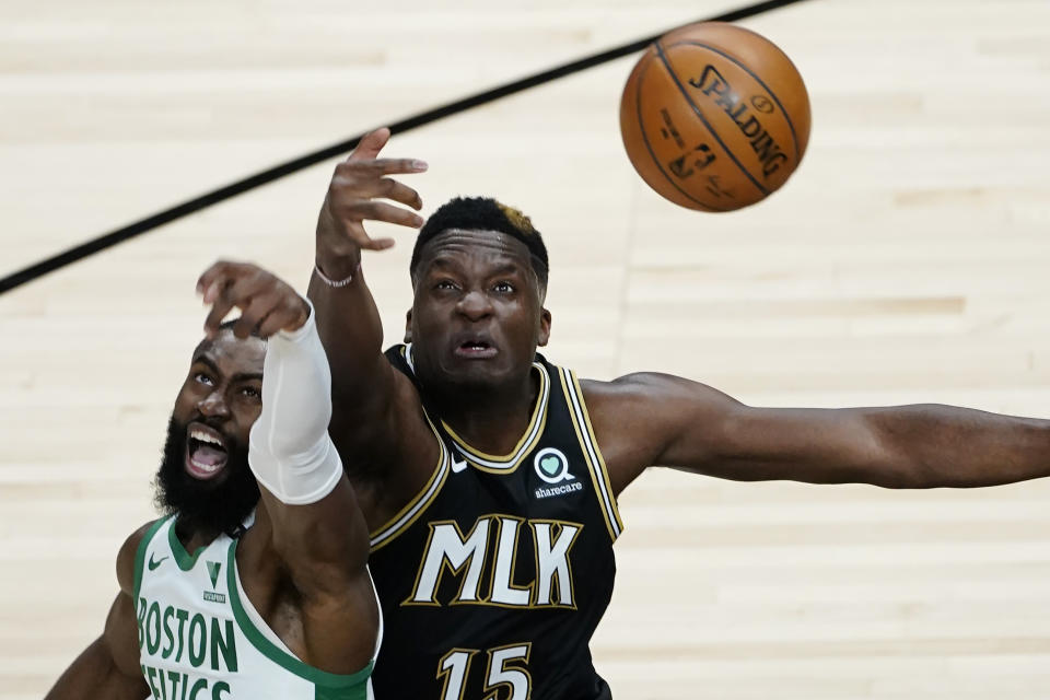 Atlanta Hawks center Clint Capela (15) and Boston Celtics guard Jaylen Brown (7) reach for a jump ball in the second half of an NBA basketball game Wednesday, Feb. 24, 2021, in Atlanta. (AP Photo/John Bazemore)