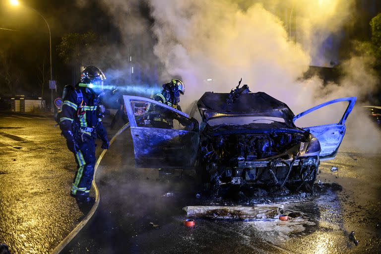 Los bomberos extinguen un coche que se incendió en Nantes, al oeste de Francia, a principios del 1 de julio de 2023, cuatro días después de que un joven de 17 años fuera asesinado por la policía en Nanterre, un suburbio occidental de París.