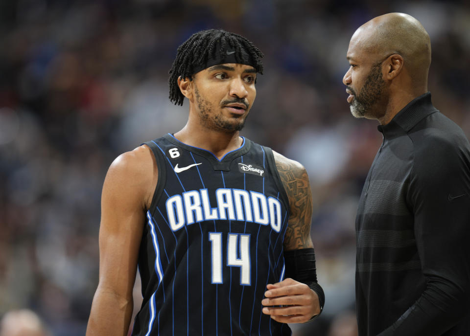 Orlando Magic guard Gary Harris, left, confers with head coach Jamahl Mosley in the first half of an NBA basketball game against the Denver Nuggets, Sunday, Jan. 15, 2023, in Denver. (AP Photo/David Zalubowski)