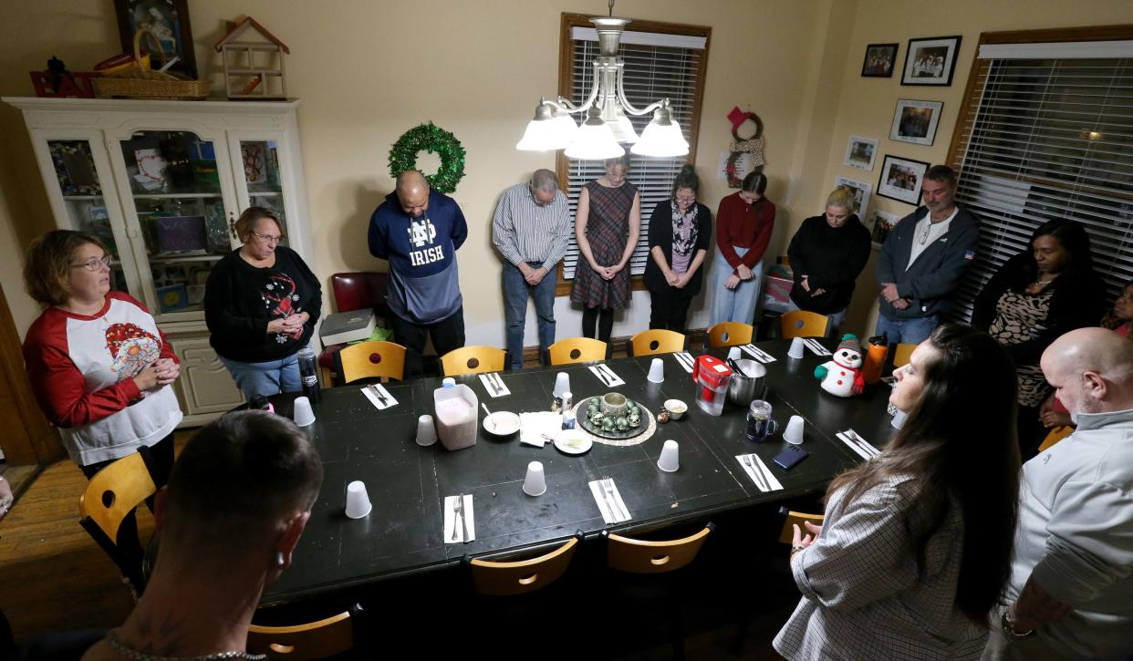 Dismas House Executive Director Maria Stancati, far left, says a prayer before the Christmas dinner Wednesday, Dec. 20, 2023, at Dismas House in South Bend.