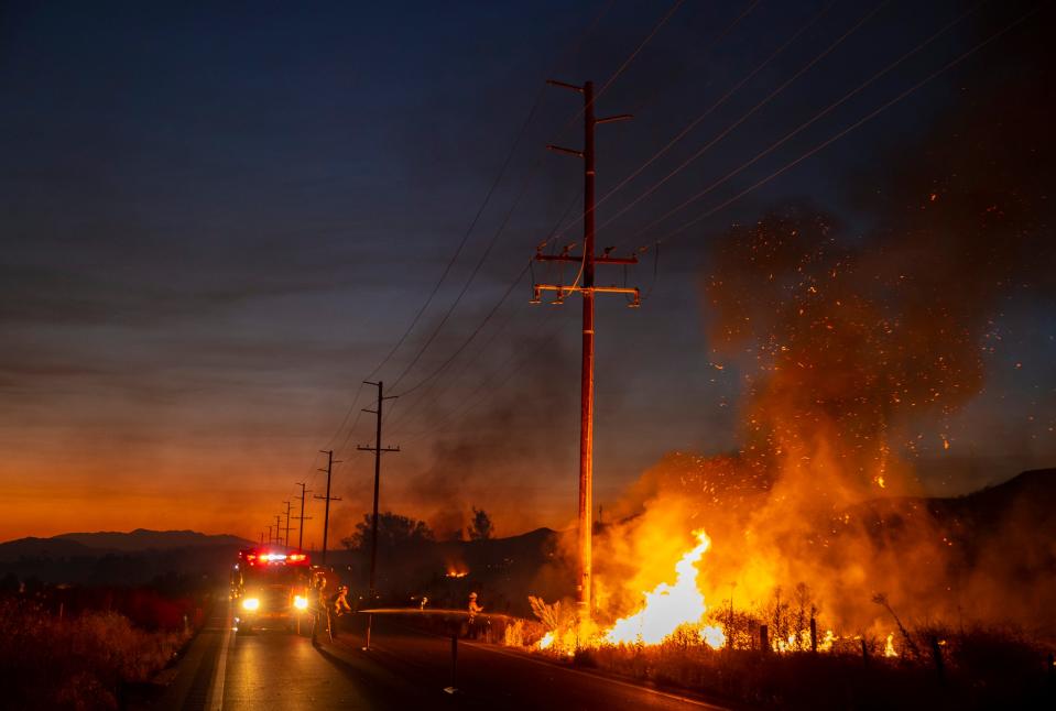 A line of fire engines work to contain the Rabbit Fire from crossing Gillman Springs Road in Moreno Valley, Calif., Friday, July 14, 2023. 