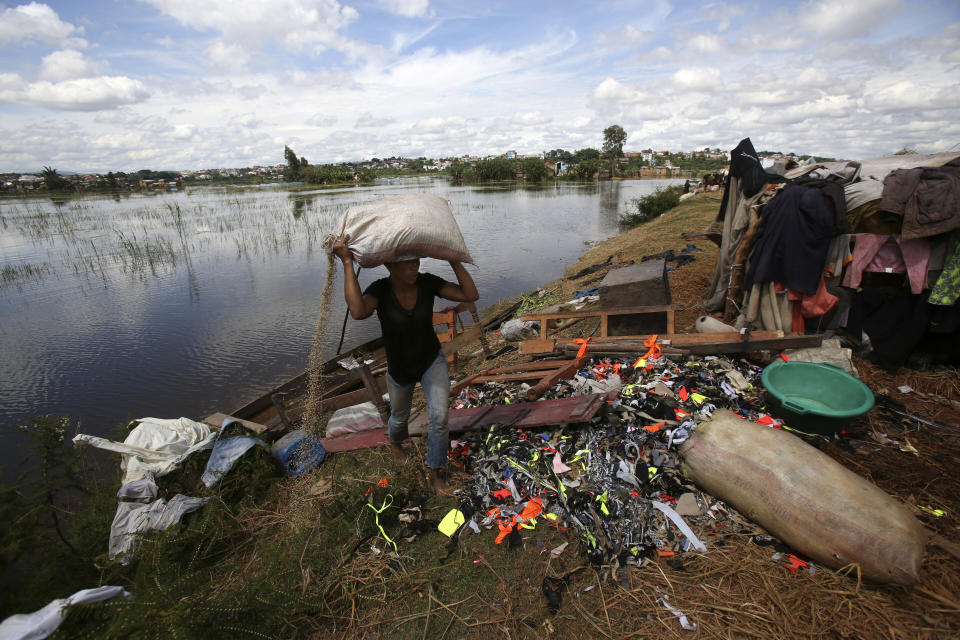 A man caries belongings from his house destroyed by tropical storm Ana in Antananarivo, Madagascar, Wednesday, Jan. 26, 2022. With heavy rains continuing, rivers in Antananarivo are rising and officials are urging residents to leave low-lying areas of the capital city and surrounding areas. (AP Photo/Alexander Joe)