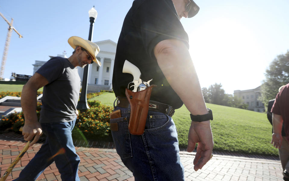 Gun rights supporters walk by the Capitol building in Richmond, Va., Tuesday, July 9, 2019, the opening for the special session called by Virginia Gov. Ralph Northam. Northam ordered lawmakers back for a special session to consider a wide range of gun-control measures, said people need "votes and laws, not thoughts and prayers" after a Virginia Beach employee shot and killed a dozen people in a city building on May 31. (Steve Earley/The Virginian-Pilot via AP)