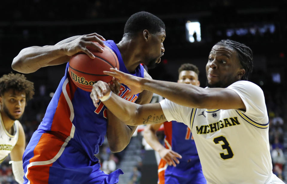 Michigan guard Zavier Simpson (3) tries to steal the ball from Florida center Kevarrius Hayes, left, during a second round men's college basketball game in the NCAA Tournament, Saturday, March 23, 2019, in Des Moines, Iowa. (AP Photo/Charlie Neibergall)