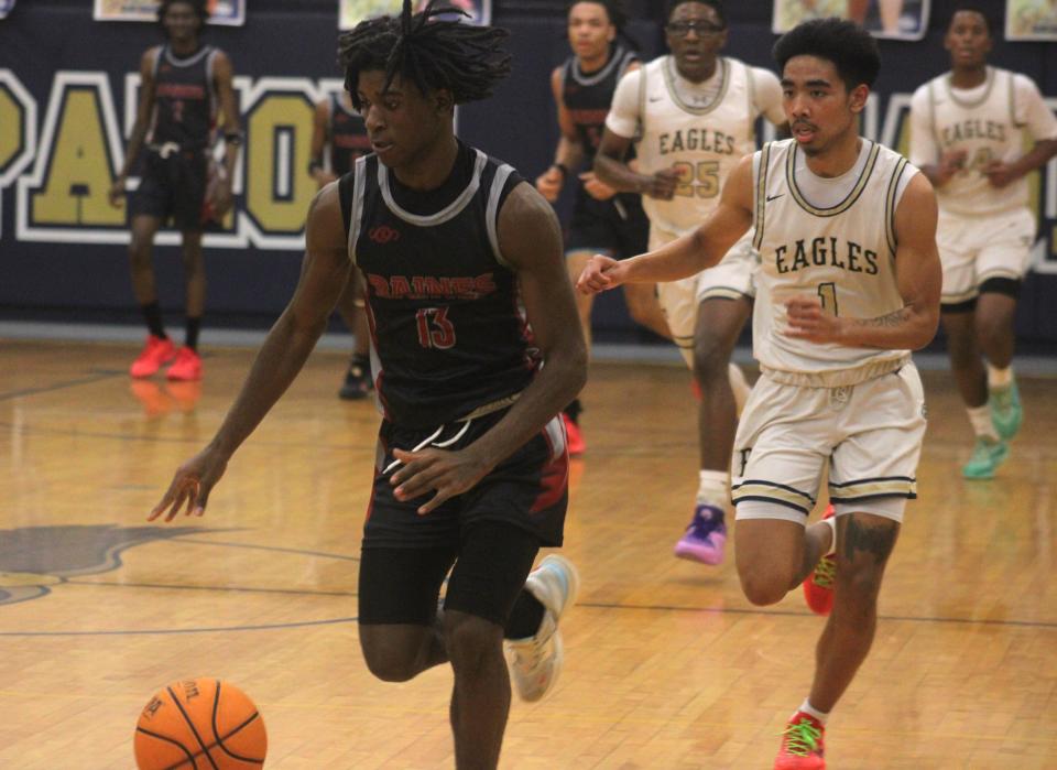 Raines guard Ta'veon Dunbar (13) dribbles up the court on the fast break as Paxon guard Jacob Delos Santos (1) pursues during a Gateway Conference high school boys basketball semifinal on January 26, 2024. [Clayton Freeman/Florida Times-Union]