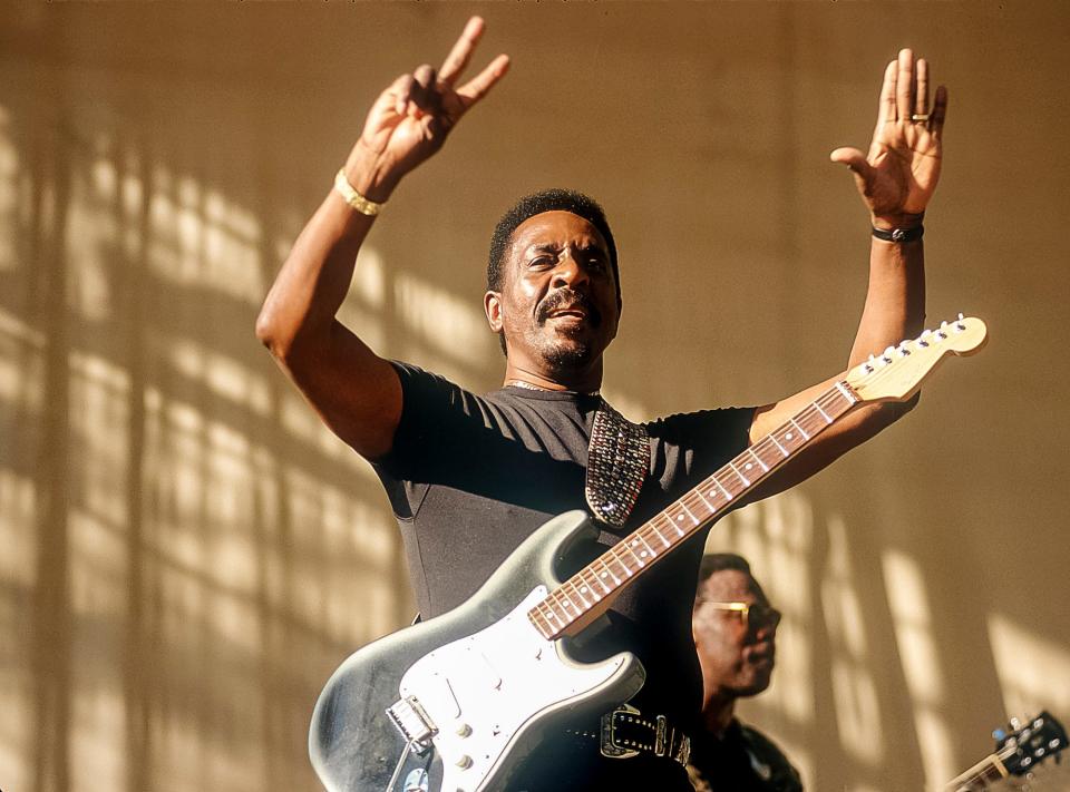 American R&B, Blues, and Rock musician and bandleader Ike Turner (born Izear Turner, 1931 - 2007) waves as he performs onstage at Central Park SummerStage, New York, New York, July 26, 1997. Visible in the background is Blues musician Joe Louis Walker on guitar.