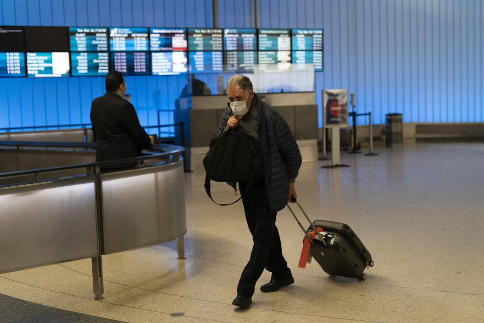 FILE - A traveler adjusts his face mask as he walks through the arrivals area at the Los Angeles International Airport in Los Angeles, Nov. 30, 2021. While all eyes are on the new and little-understood omicron variant, the delta form of the coronavirus isn't finished wreaking havoc in the U.S. (AP Photo/Jae C. Hong, File)
