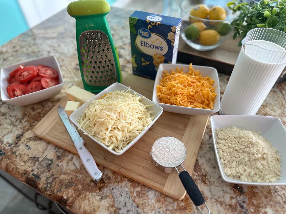 Ingredients for mac and cheese on the counter including shredded cheese and flour