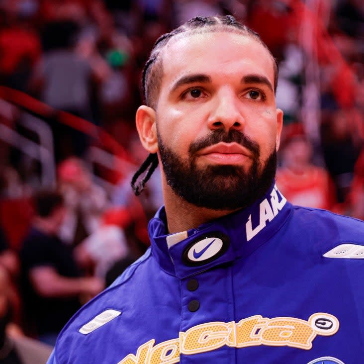 Drake in a Lakers jacket with a focused expression at a basketball game