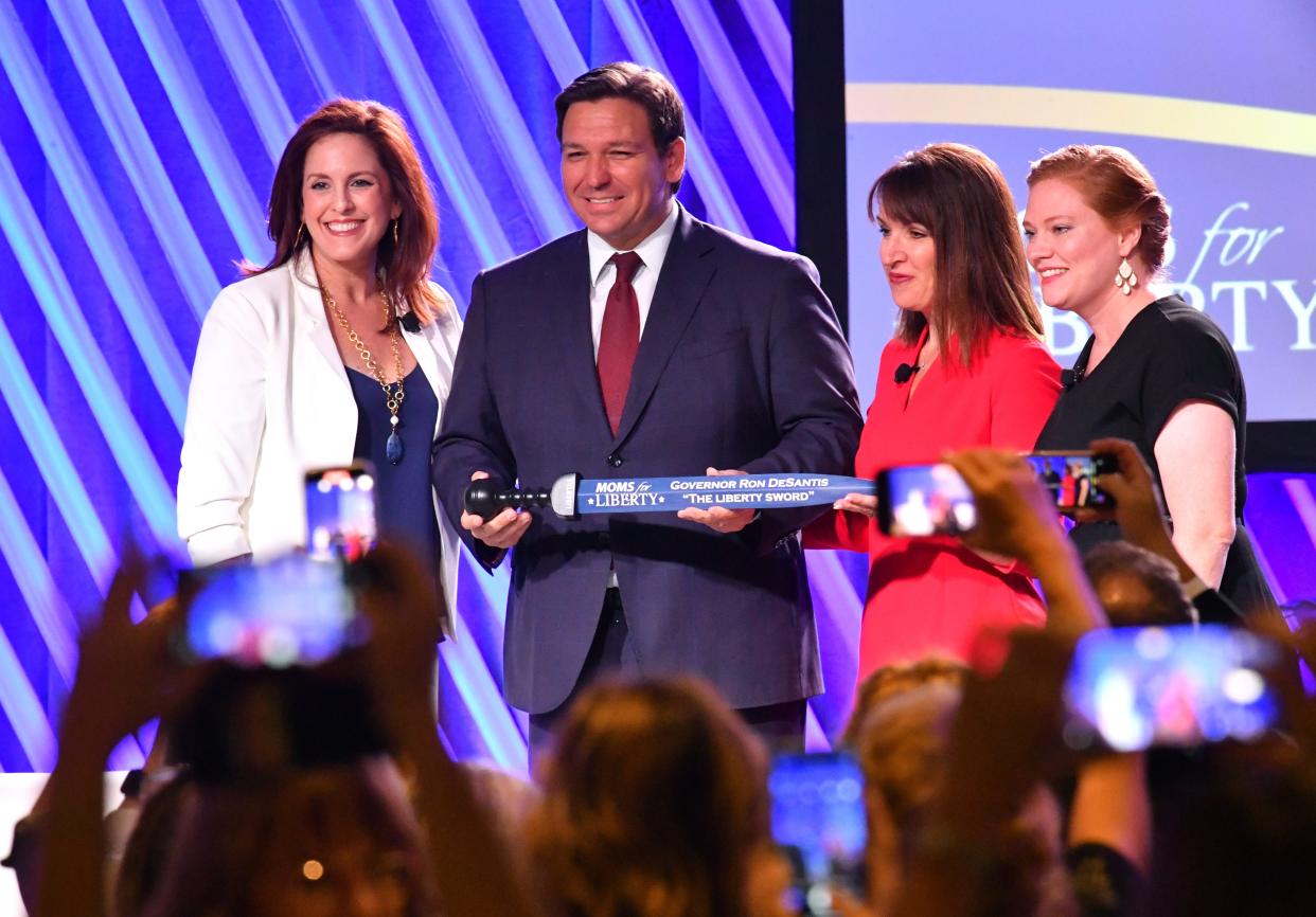 Florida Gov. Ron DeSantis is presented "The Sword of Liberty" by Moms for Liberty co-founders Tiffany Justice, left, and Tina Descovich, right, and executive director of program outreach Marie Rogerson, far right, during the Moms for Liberty National Summit in Tampa.