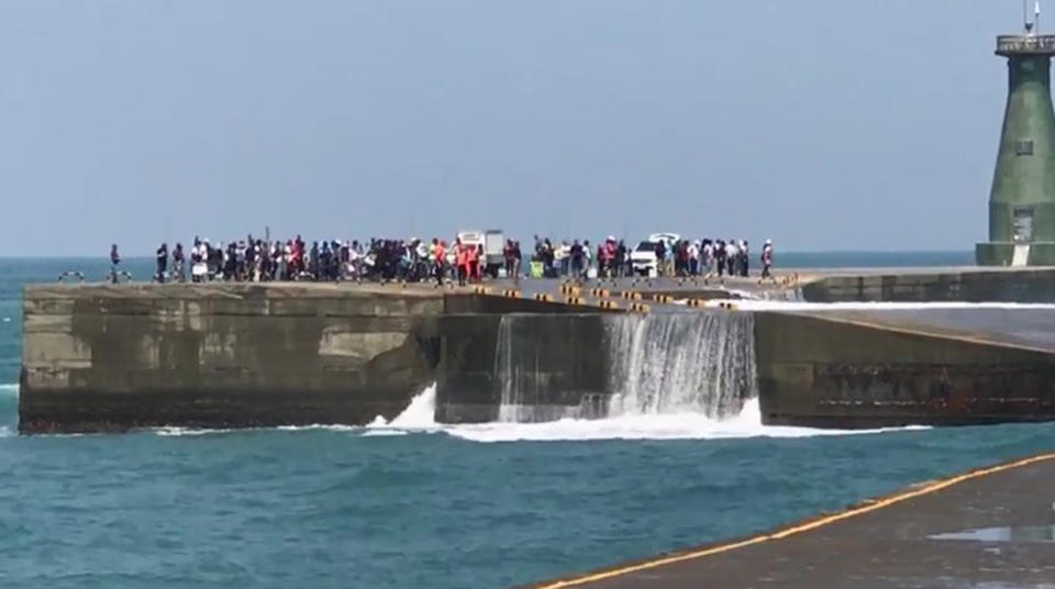 100多名釣客17日上午參加在基隆港東岸堤防舉辦的釣魚活動，一輛廂型車遭湧浪襲擊翻覆落海，104名釣客受困堤防，幸最後安全撤離。（中央社/翻攝畫面）