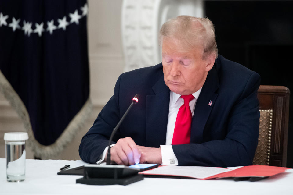 Then-President Donald Trump uses his cellphone during a roundtable discussion at the White House. (Saul Loeb / AFP via Getty Images)