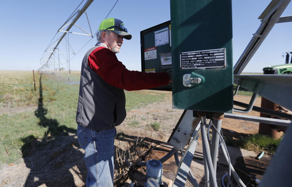 Tim Black adjusts the water application rate on a pivot for a newly planted field on his Muleshoe, Texas, farm on Monday, April 19, 2021. The longtime corn farmer now raises cattle and plants some of his pasture in wheat and native grass – and rations water use -- because the Ogallala Aquifer is drying up. (AP Photo/Mark Rogers)