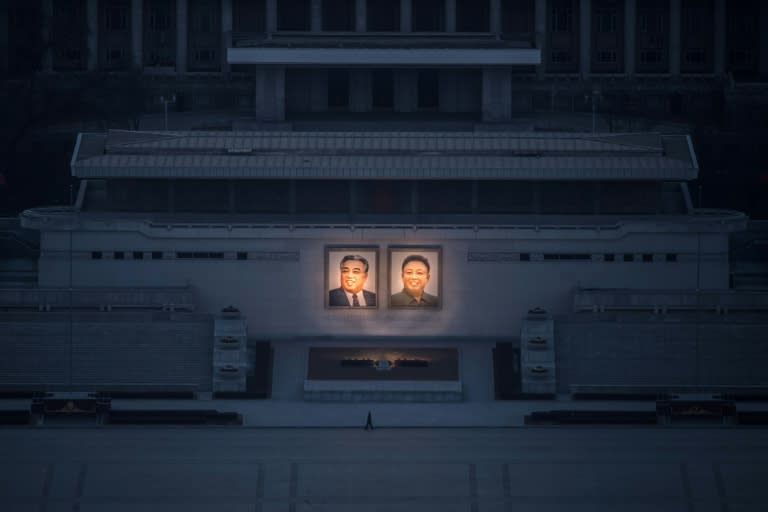 A pedestrian passes portraits of late North Korean leaders Kim Il-Sung (L) and Kim Jong-Il in Pyongyang, seen from the landmark Juche tower on February 17, 2017