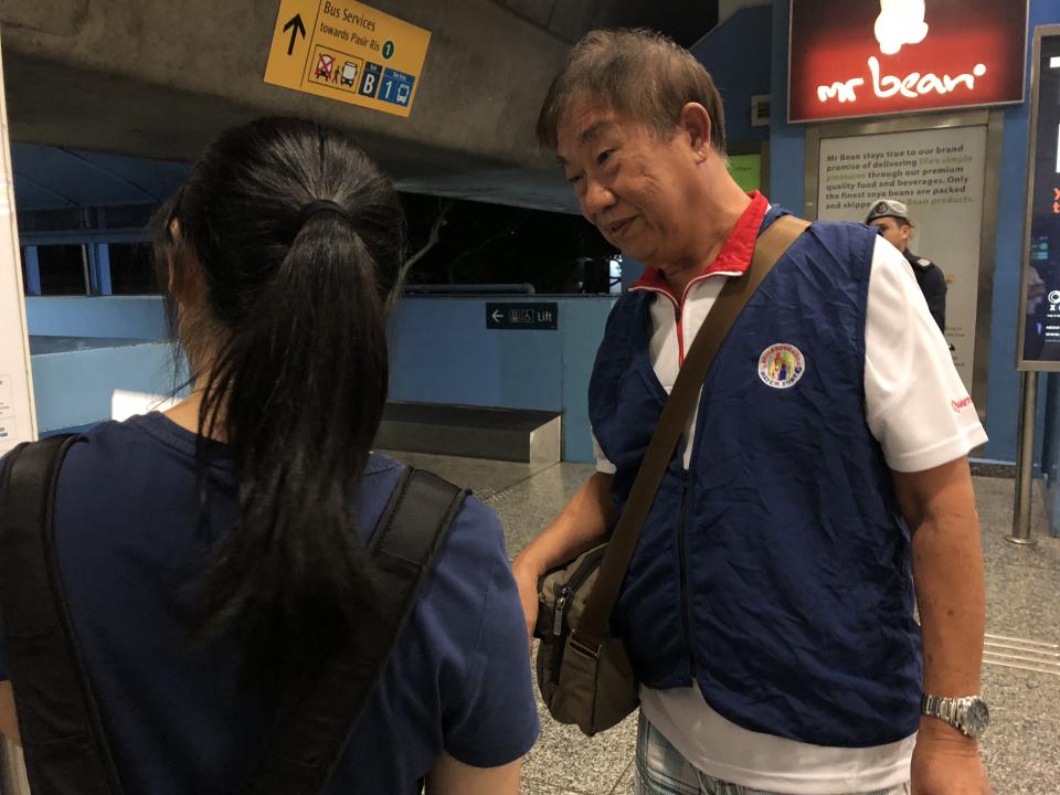 Fellow volunteer Robert Low, 70, speaking to a commuter outside the gantry at Queenstown MRT Station on 17 August, 2018. (PHOTO: Wong Casandra/Yahoo News Singapore)