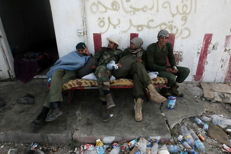 Libyan rebels rest in Uqayla, 20 kms (12 miles) east of Ras Lanuf. Libyan leader Moamer Kadhafi suffered a major blow Wednesday with the defection of his foreign minister even as his forces again proved too strong for the rebels' rag-tag army
