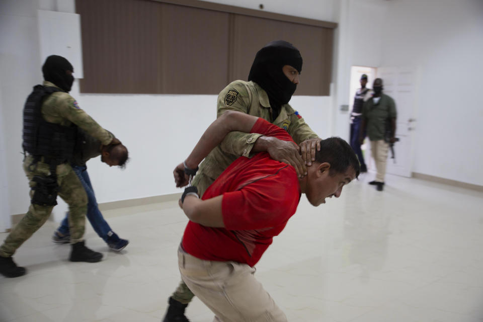 FILE - Two suspects in the assassination of Haiti's President Jovenel Moise are moved to be displayed to the media at the General Direction of the police in Port-au-Prince, Haiti, Thursday, July 8, 2021. Colombian President Iván Duque said Wednesday, April 13, 2022, that there is evidence and testimony that seriously implicates “practically all” of the former Colombian soldiers who are arrested in Haiti in relation to the assassination of Haitian President Jovenel Moïse. (AP Photo/Odelyn Joseph, File)