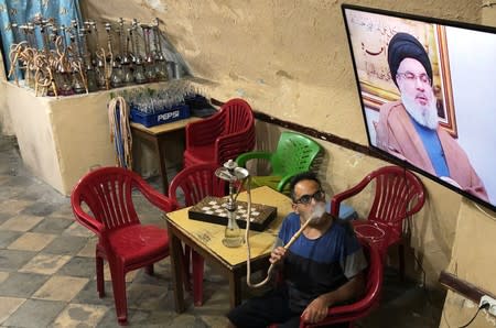 Man watches Lebanon's Hezbollah leader Sayyed Hassan Nasrallah on TV inside a coffee shop in Sidon