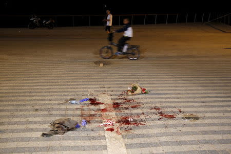 A boy rides past blood stains where, according to Israeli police spokesperson, at least 10 Israelis were stabbed, in the popular Jaffa port area of Tel Aviv, Israel March 8, 2016. REUTERS/Amir Cohen