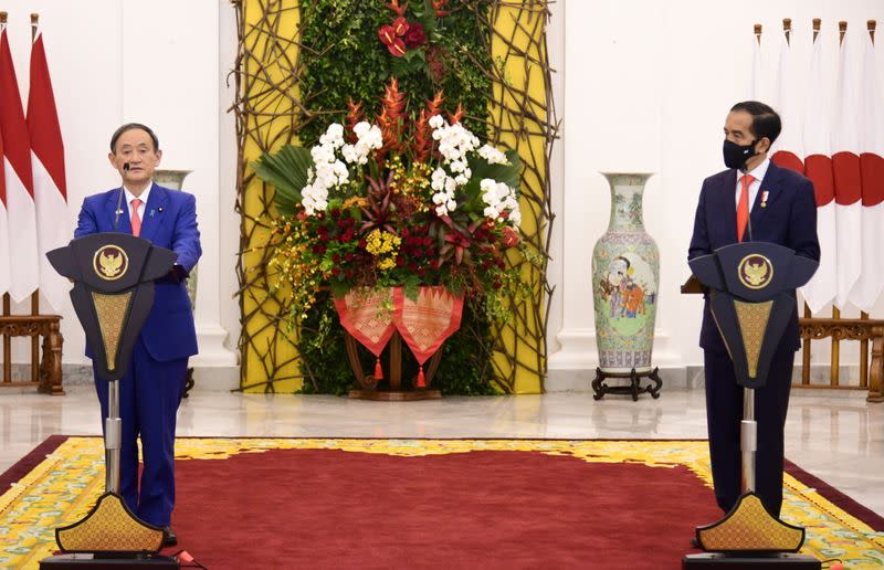 Japan's Prime Minister Suga speaks as Indonesian President Widodo listens during a joint statement following their meeting at Indonesian Presidential Palace in Bogor