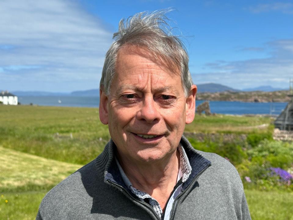 John Beveridge smiling with a scenic coastal backdrop