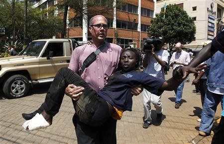 A journalist rescues a woman injured in a shootout between armed men and the police at the Westgate shopping mall in Nairobi September 21, 2013. REUTERS/Thomas Mukoya