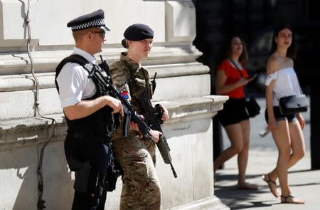 Tourists walk past a soldier and an armed police officer on duty on Whitehall in London, Britain, May 26, 2017. REUTERS/Peter Nicholls