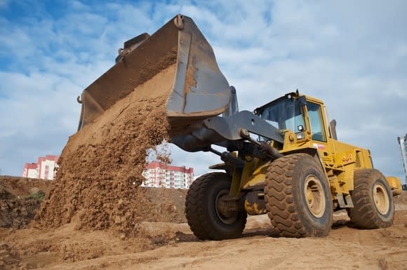 Excavator dumping sand into a pile.