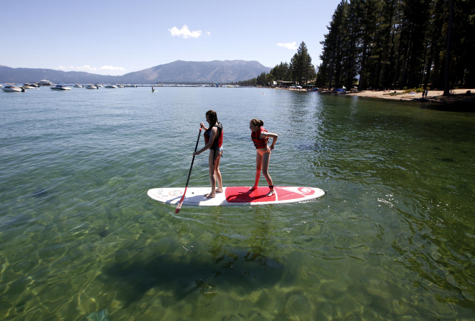 FILE - In this Aug. 20, 2019, file photo, Freya Mayo, left, and her sister Evie, of London, England, try out a paddle board on Lake Tahoe near South Lake Tahoe, Calif. The fallout from humanity's addition to plastics is showing up in the waters of Lake Tahoe. Scientists detected microplastics at several locations around the lake for the first time this year and are working to understand what that means for human health and the environment of the Tahoe Basin. (AP Photo/Rich Pedroncelli, File)