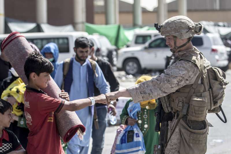 2021年8月24日，一名護衛喀布爾機場的美軍陸戰隊員，正與一位阿富汗男孩互碰拳頭。（美聯社）