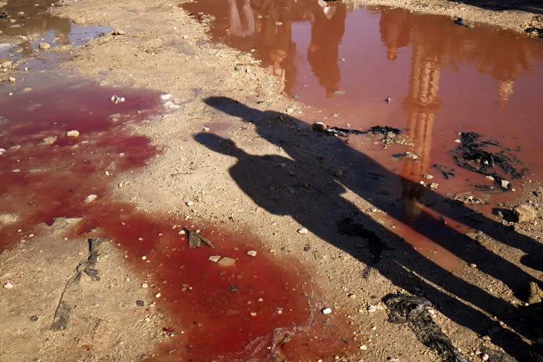 Libyans check the aftermath of an explosion in the eastern city of Benghazi on January 24, 2018