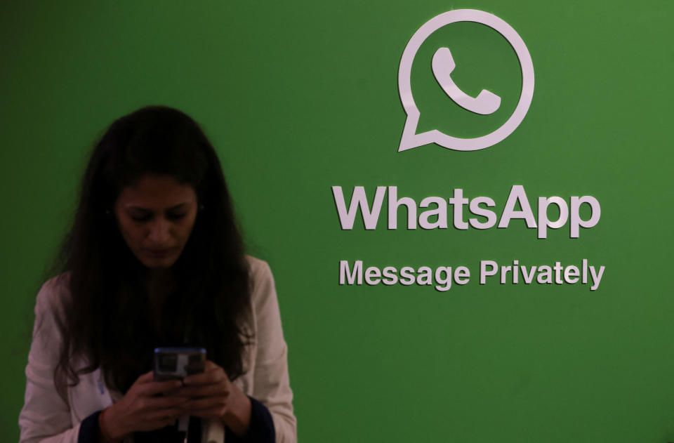 A woman uses her phone next to a logo of the WhatsApp application during Global Fintech Fest in Mumbai, India September 20, 2022. REUTERS/Francis Mascarenhas
