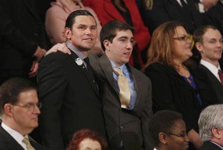 Boston Marathon bombing survivor Jeff Bauman, who had to have both his legs amputated after being injured in the blasts, stands with his rescuer Carlos Arredondo (L) before the start of U.S. President Barack Obama's State of the Union speech on Capitol Hill in Washington January 28, 2014. REUTERS/Gary Cameron