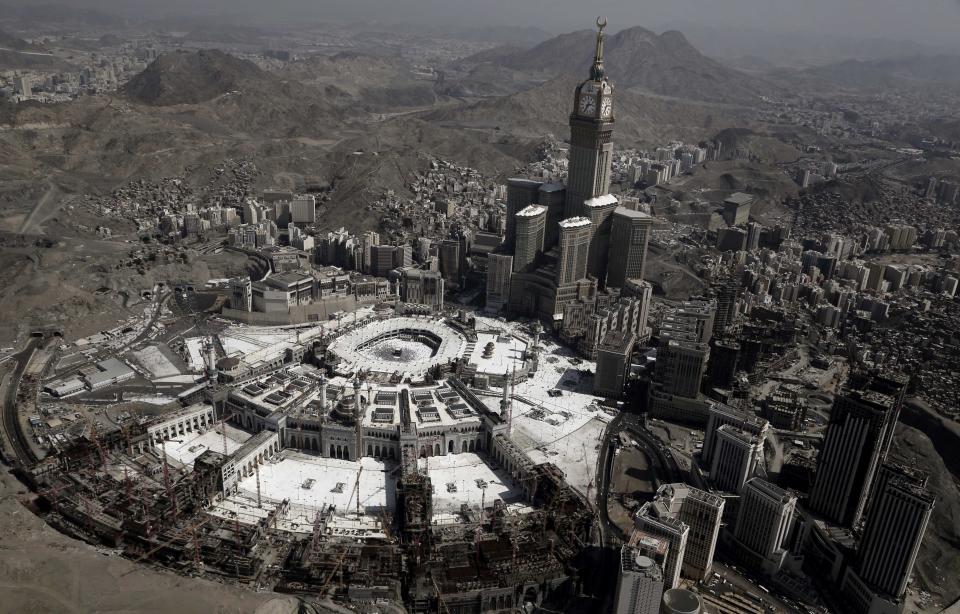 FILE - In this Sept. 13, 2016 file photo, the Abraj Al-Bait Towers with the four-faced clocks stands over the holy Kaaba, as Muslims encircle it inside the Grand Mosque, during the hajj pilgrimage, in Mecca, Saudi Arabia. Over 2 million Muslims from around the world are beginning the five-day hajj pilgrimage on Friday, Aug, 8, 2019. They will take part in a series of rituals intended to bring about greater humility and unity among Muslims. (AP Photo/Nariman El-Mofty, File)